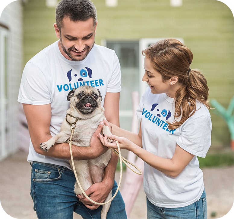 Two Project Watson volunteers holding a happy pug