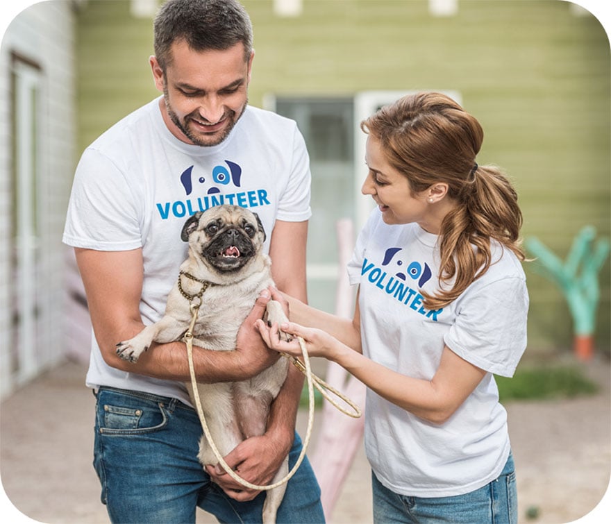 Two Project Watson volunteers holding a happy pug